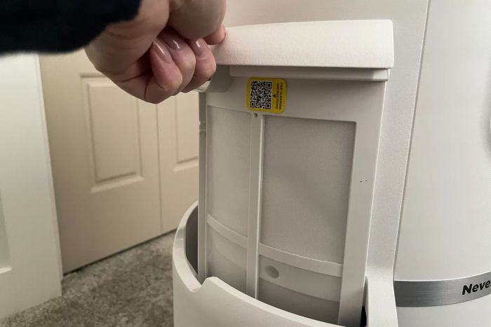 A person opens the filter compartment of the Shark NeverChange Air Purifier MAX.