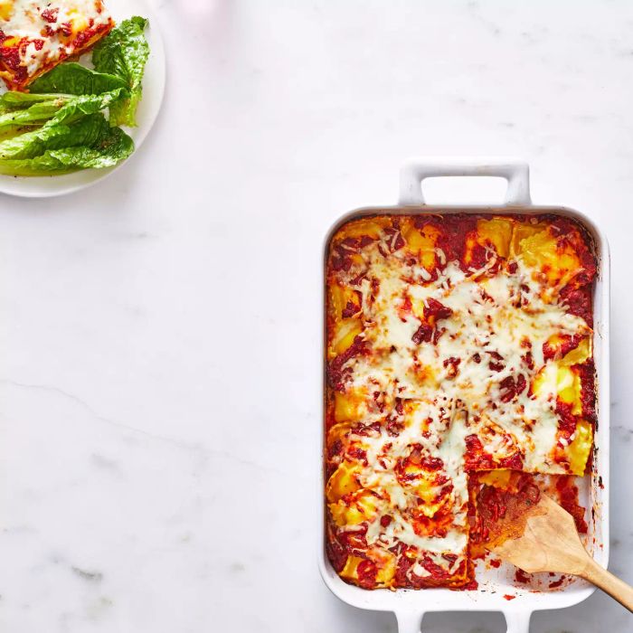 Cheesy Baked Ravioli casserole in a baking pan with romaine salad on the side
