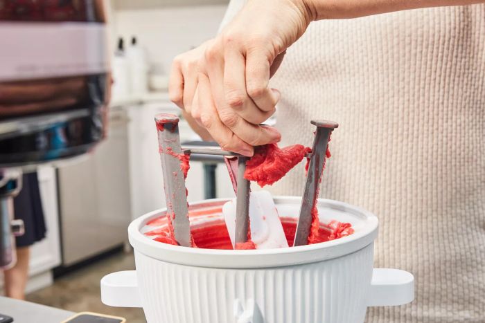 A hand detaching the KitchenAid Ice Cream Maker Attachment after making sorbet