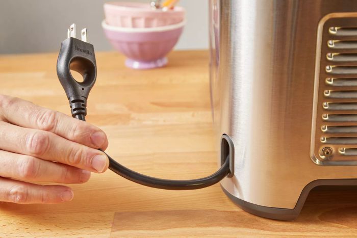 Closeup of a hand grasping the plug for the Breville The Smart Scoop Ice Cream Maker