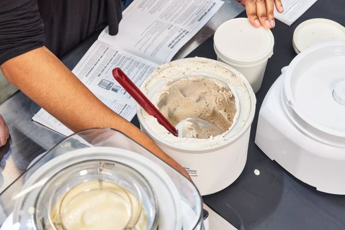 A person sealing a container of ice cream made with the Cuisinart 1.5-Quart Frozen Yogurt, Ice Cream, & Sorbet Maker, while more ice cream sits in a bucket with a spatula