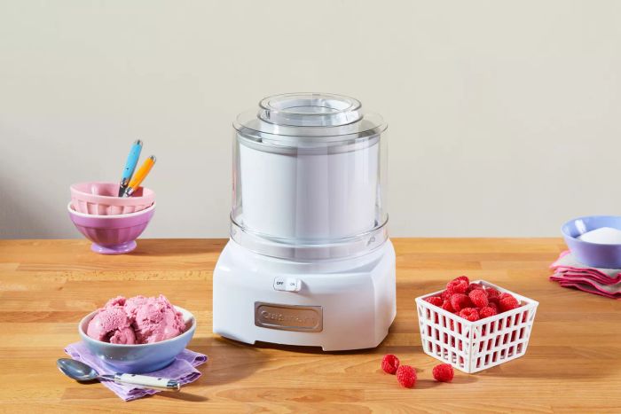 Cuisinart 1.5-Quart Frozen Yogurt, Ice Cream, & Sorbet Maker displayed on a wooden surface with ice cream and raspberries