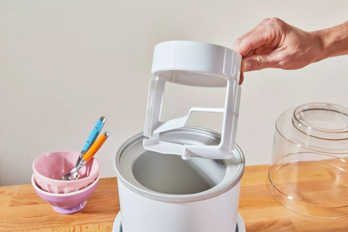 A hand removes the paddle from the Cuisinart 1.5-Quart Frozen Yogurt, Ice Cream, & Sorbet Maker