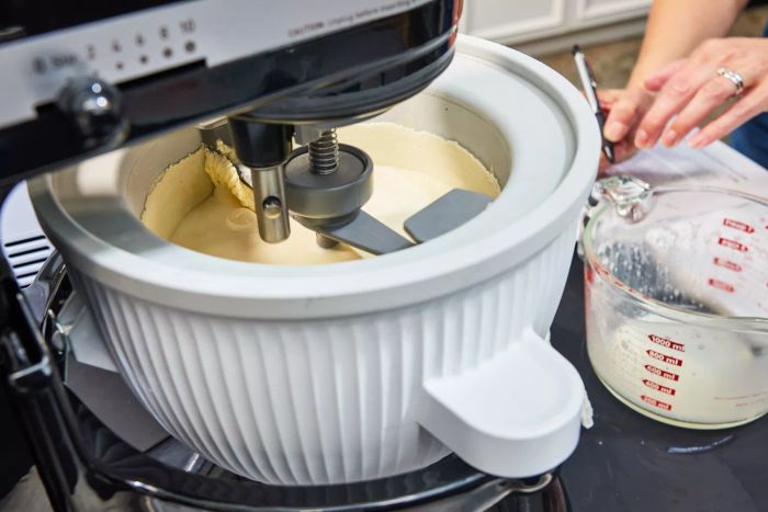 The KitchenAid Ice Cream Maker Attachment churning ice cream with a person writing in the background