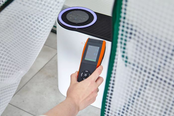 A person is shown taking a reading from the Aroeve MK04 Air Purifier.