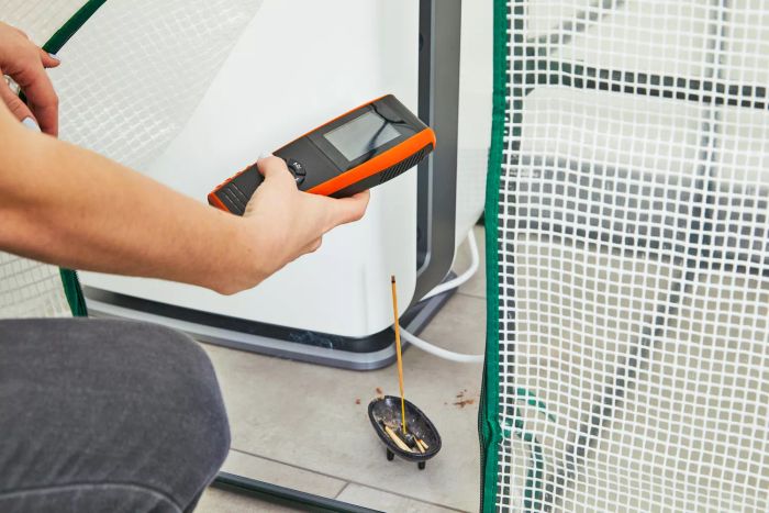 Person taking an air reading while an incense stick burns by the Alen BreatheSmart 75i Air Purifier for Pet Odor and Dander