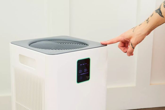 An individual adjusting the corner of the Kenmore 1500e Air Purifier with SilentClean HEPA Technology