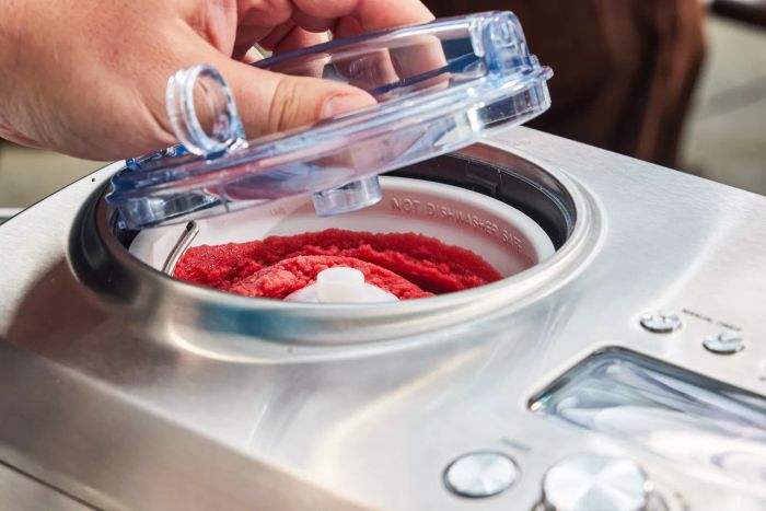 A hand lifting the lid to expose the sorbet inside the Breville The Smart Scoop Ice Cream Maker