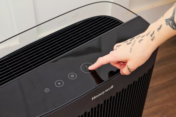 A person pressing the power button on the Honeywell HPA5300 InSight HEPA Air Purifier.