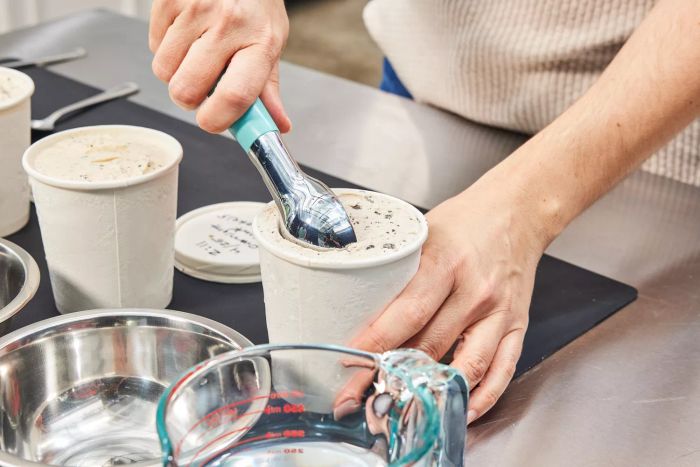 Hands scooping ice cream from one of three pint containers