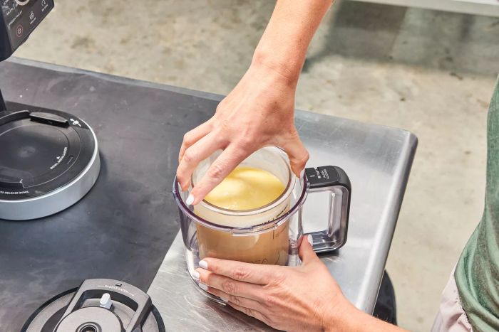 Hands placing the ice cream mix container into the Ninja Creami Deluxe 11-in-1 XL Ice Cream Maker