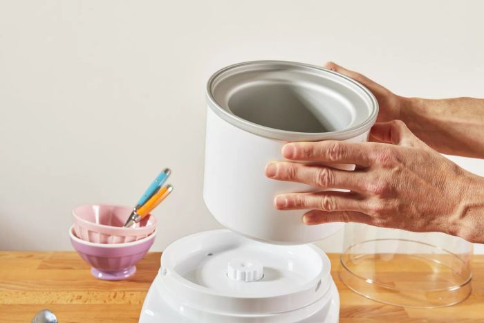 Hands lifting the drum of the Cuisinart 1.5-Quart Frozen Yogurt, Ice Cream, & Sorbet Maker over the base