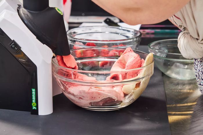 Pink soft serve being poured into a glass bowl from the Yonanas Classic Soft-Serve Dessert Maker