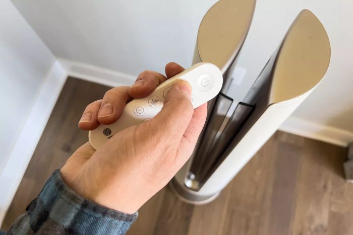 A person adjusts the LG PuriCare AeroTower True HEPA Air Purifying Fan using the remote control.