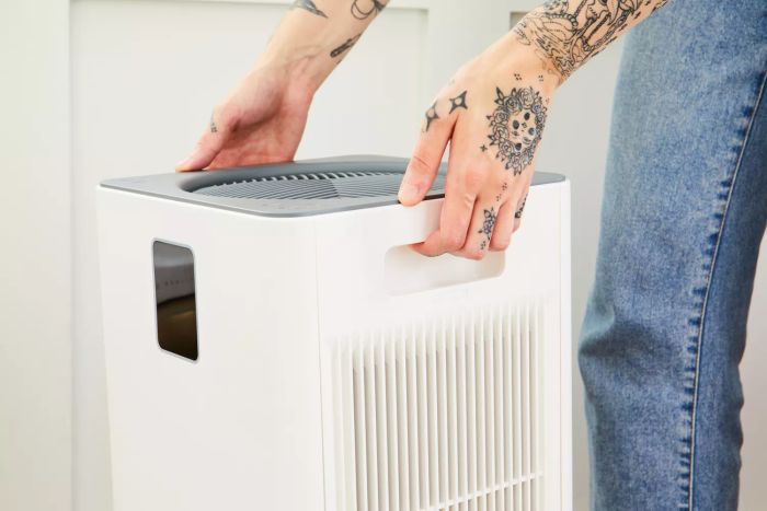 A person fine-tuning the Kenmore 1500e Air Purifier with SilentClean HEPA Technology