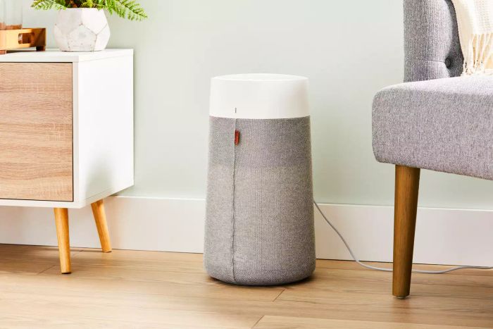 The Blueair Blue Pure 411i Max Air Purifier shown on a wooden floor between a console table and a chair