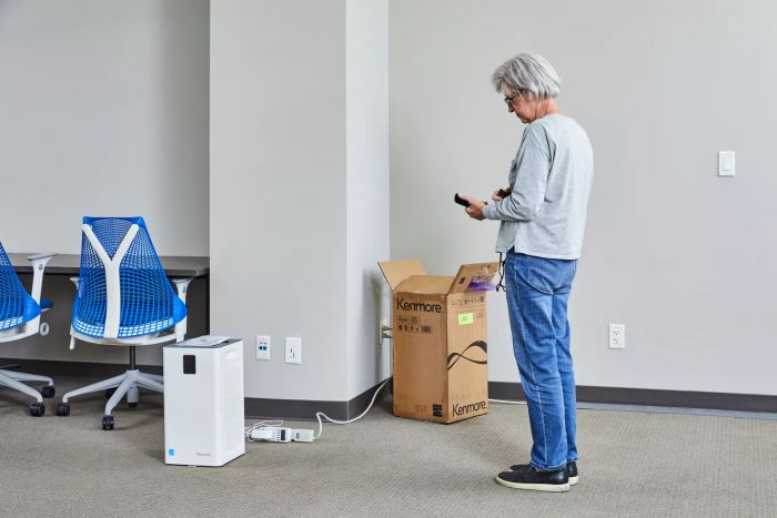 A person assessing the air quality near the Kenmore 1500e Air Purifier.
