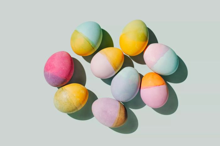 A variety of colorful eggs set against a pastel blue background. Easter-themed minimalist style. Overhead view, flat lay.