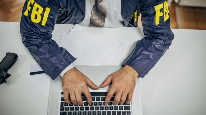 An FBI officer working on a laptop.