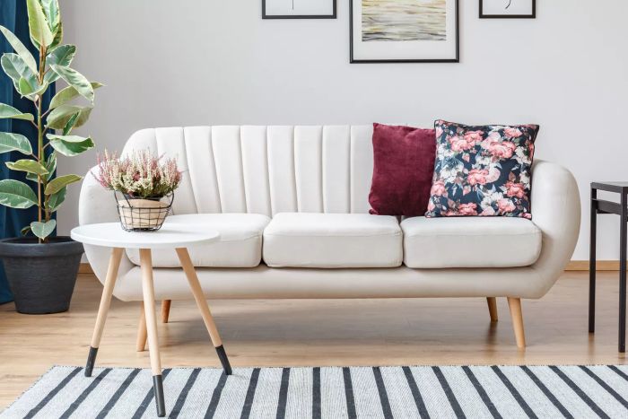 Sophisticated beige sofa with wooden legs and decorative cushions in a vibrant living room adorned with wood paneling.