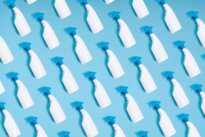 Pattern of spray bottles repeated on a blue backdrop