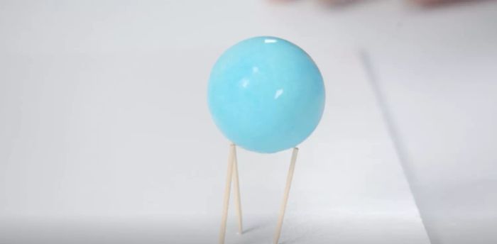 A blue-dyed egg drying on toothpicks