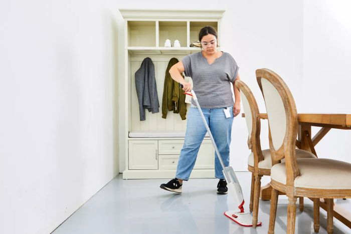 person cleaning under dining table with Panda Grip Microfiber Spray Mop