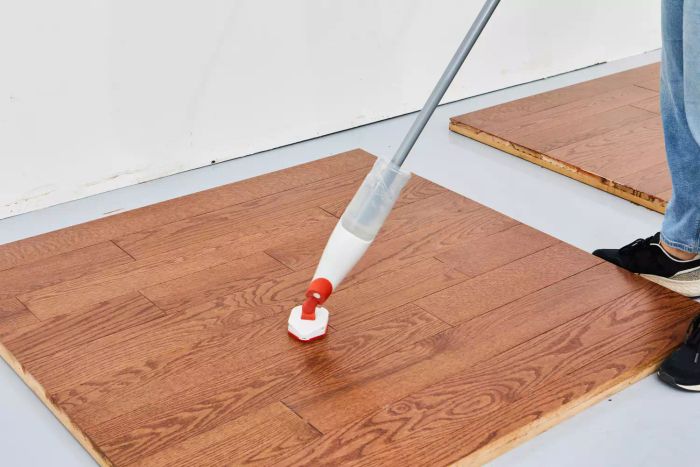 The slide-out scrubber of the OXO Good Grips Microfiber Spray Mop being used to clean a spot on a wooden floor.