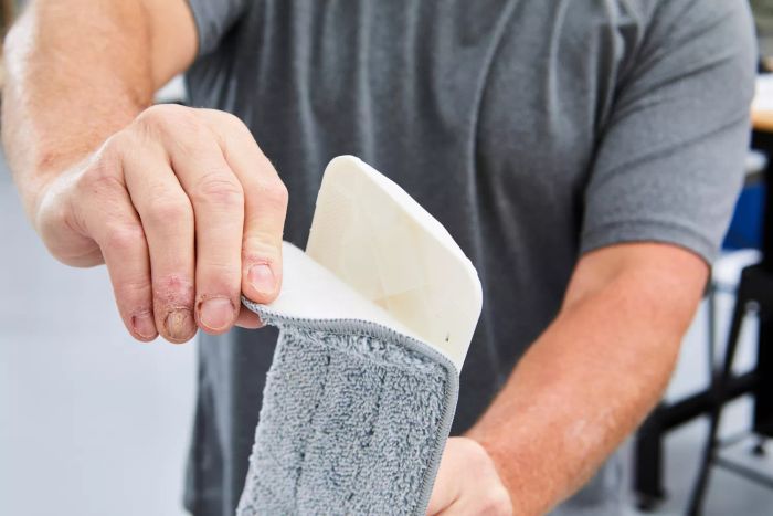 hands peeling microfiber mop pad off of mop head