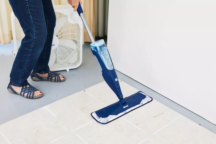 A person using the Bona Hardwood Floor Premium Spray Mop to clean a tile floor.