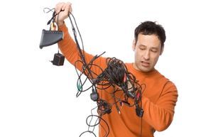 A young man struggles with a tangled mess of electronic charging cables.