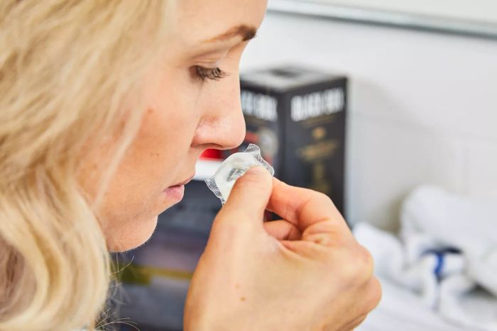 A woman inhales the scent of a Dropps Sensitive Skin & Baby Laundry Detergent Pod
