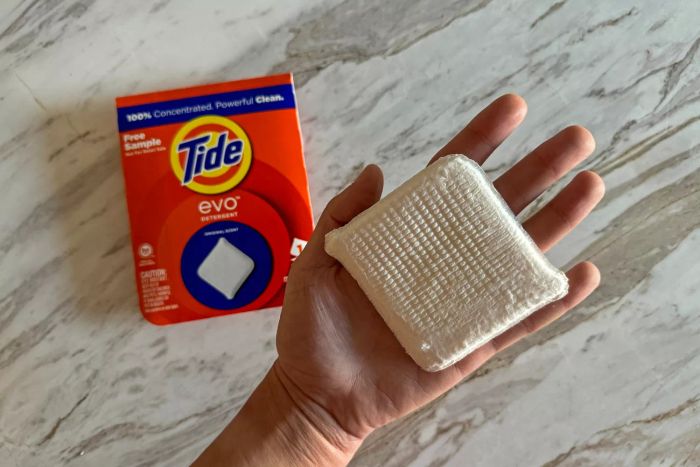 A person holds the Tide Evo Concentrated Detergent in the palm of their hand.