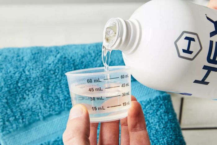 Hands pouring HEX Performance Laundry Detergent into a measuring cup