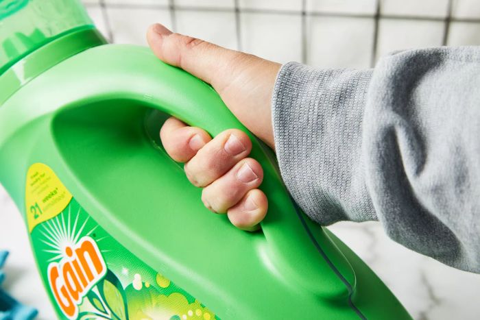 Holding a bottle of Gain Original Liquid Laundry Detergent with Aroma Boost