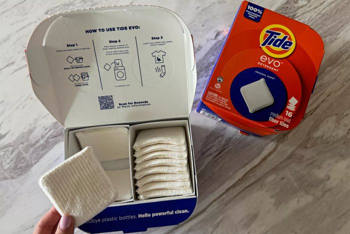 A person takes Tide Evo Concentrated Detergent out of its box.