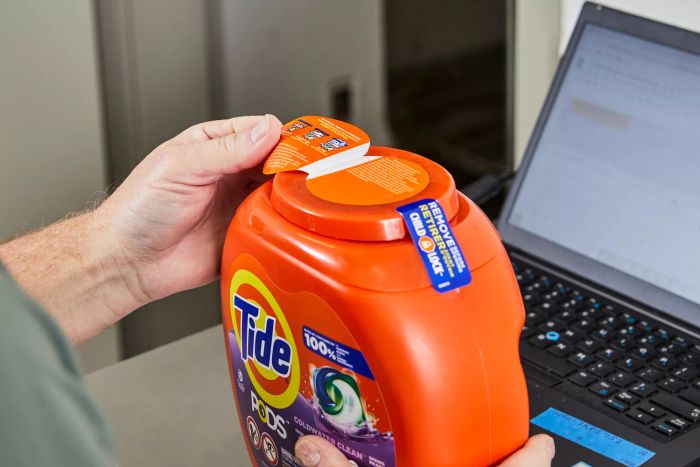 A person reading the instructions on the lid of Tide Pods Spring Meadow Laundry Detergent