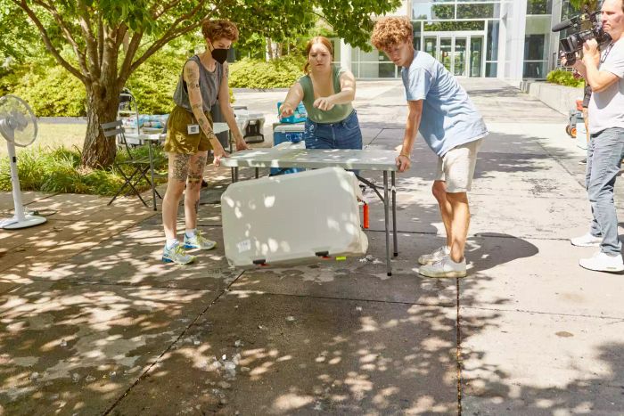 Person pushing the Lifetime 65-Quart High-Performance Cooler off a table while others observe