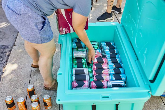 Person filling Orca 140 Qt. Cooler with soda cans