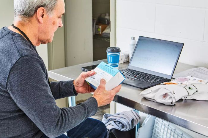A person holding a box of Bryt Laundry Detergent Sheets in front of a computer on a table