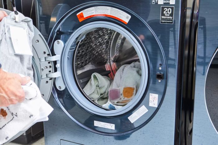 A person adding clothes to a washing machine to be cleaned with Clean People Laundry Detergent Pods