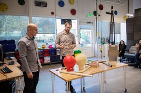 Two members of the Google X team present the round antenna and chunky package for Google Loon, an experimental Internet service powered by balloons.