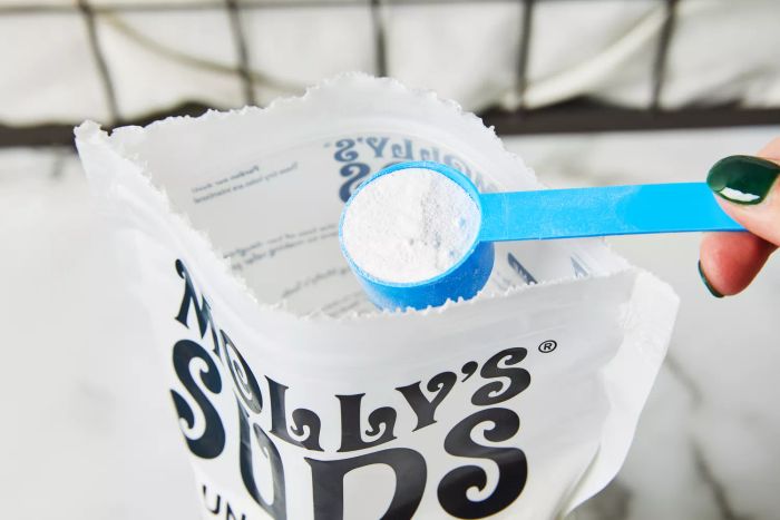 Scooping Molly's Suds Unscented Laundry Detergent Powder from the package