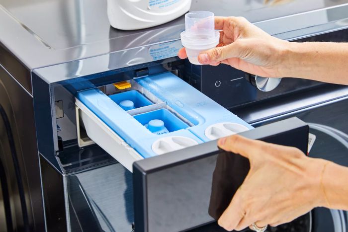 Hand pouring HEX Performance Laundry Detergent into the washing machine drawer