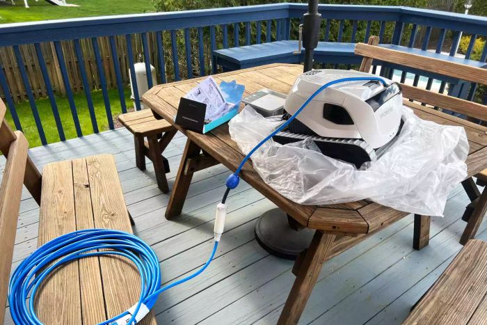 Dolphin Explorer E50 Robotic Pool Cleaner unboxed, placed on a wooden table on a deck