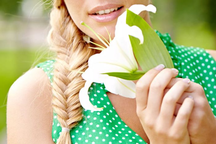 A woman holding a flower with a chic fishtail braid