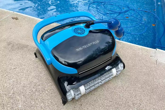 Dolphin Nautilus CC Plus Robotic Pool Cleaner resting on the edge of a cement pool