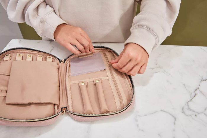 A person adjusting the Bagsmart Jewelry Organizer Bag on a marble tabletop
