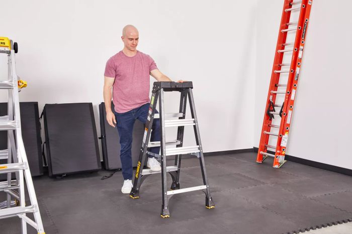 A person stands on a DeWalt 4-Foot Fiberglass Step Ladder.