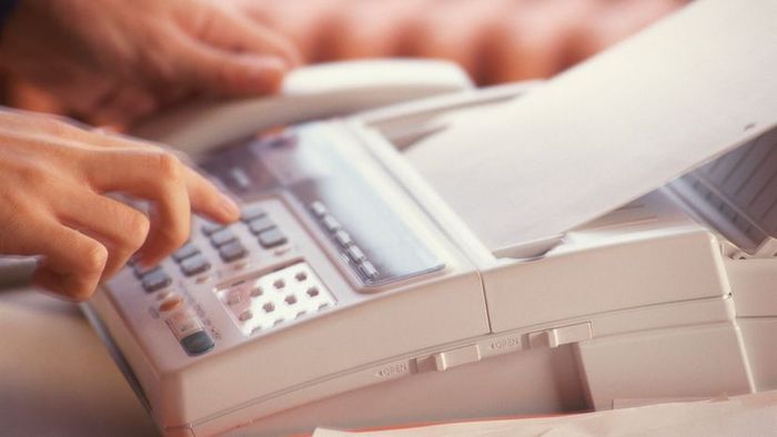 A person operating a fax machine.